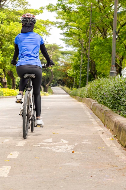 Vista traseira da mulher asiática usando passeio de bicicleta de capacete