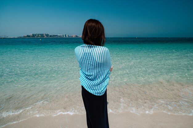 Vista traseira da mulher caminhando no mar em Dubai