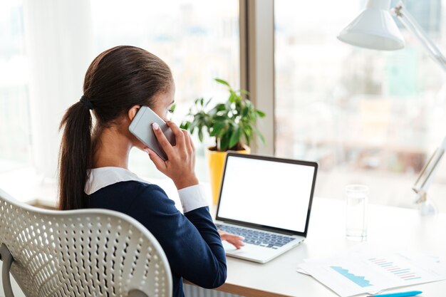 Vista traseira da mulher de negócios na África falando ao telefone no escritório