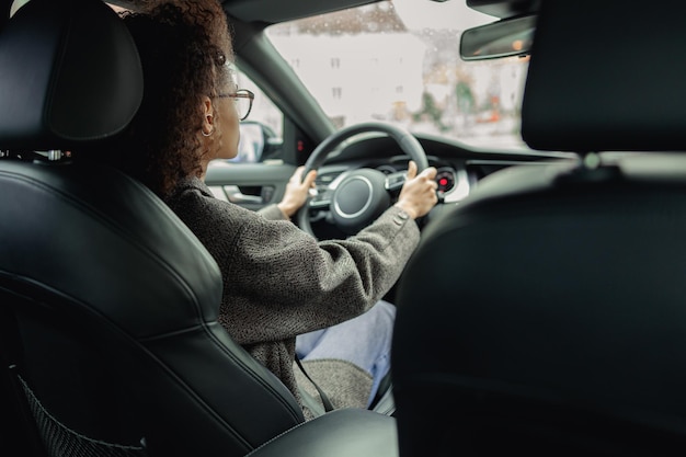 Vista traseira da mulher dirigindo o carro e segurando as duas mãos no volante a caminho do trabalho