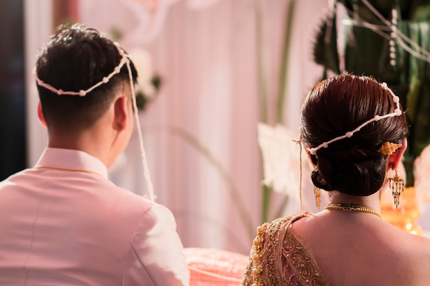 Vista traseira da noiva e do noivo em uma cerimônia de casamento de estilo tailandês.