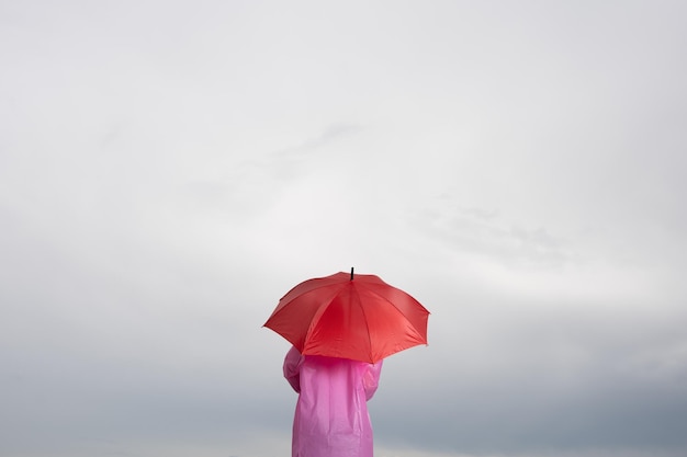 Vista traseira da pessoa segurando guarda-chuva sob céu nublado