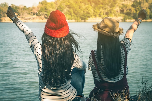 Foto vista traseira de amigos sentados no lago contra as árvores