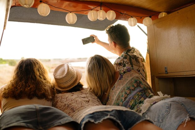 Vista traseira de amigos tirando selfie dentro de uma van