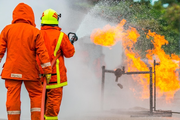 Foto vista traseira de bombeiro pulverizando água sobre o fogo enquanto estava de pé na rua