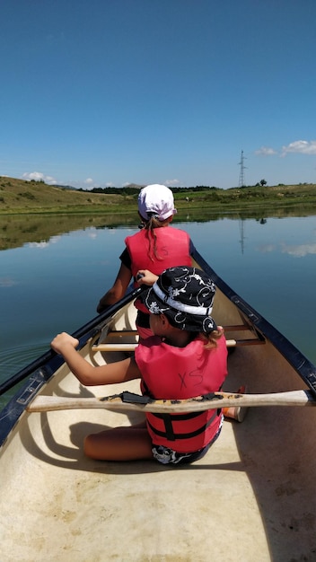 Foto vista traseira de crianças em um barco no lago contra o céu