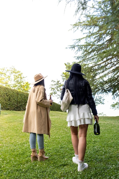 Vista traseira de duas meninas chegando no parque com uma bebida para comemorar