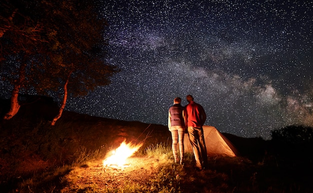 Vista traseira, de, duas pessoas, agarrando um ao outro, olhar, céu estrelado, com, via láctea