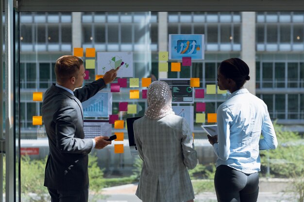 Foto vista traseira de empresários discutindo sobre notas adesivas no escritório. empresa moderna inicia novo conceito de negócio com empresário trabalhando duro