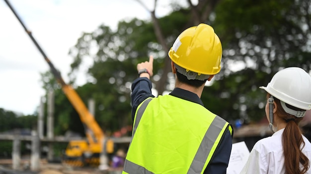 Vista traseira de engenheiros civis e especialistas verificando o plano no canteiro de obras Conceito de construção do engenheiro da indústria