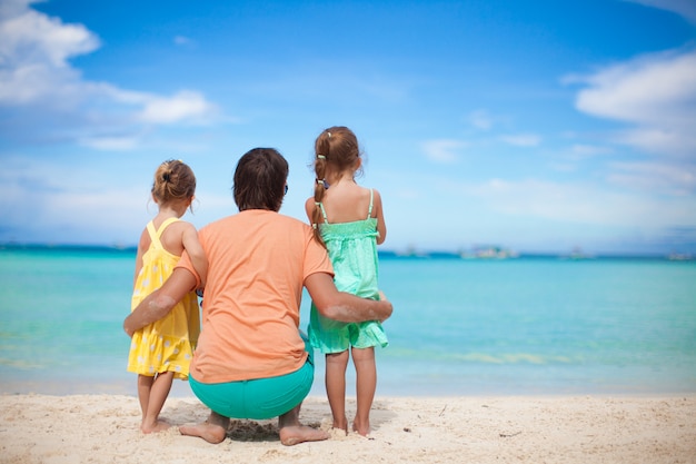 Vista traseira, de, feliz, pai, com, seu, dois, filhas, ligado, praia tropical, férias