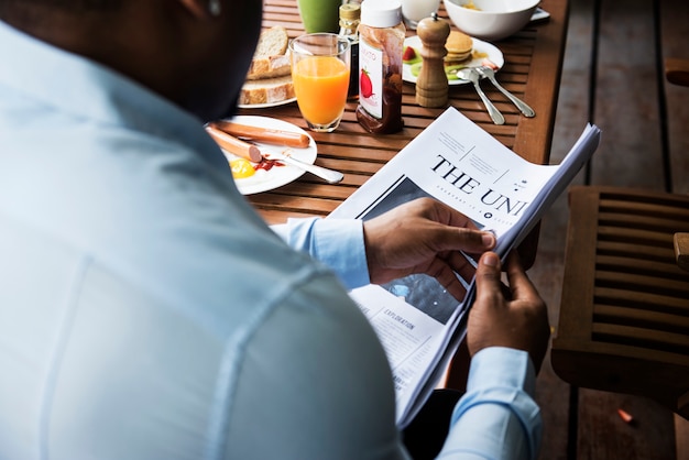 Vista traseira, de, homem preto, jornal leitura, enquanto, tendo, pequeno almoço