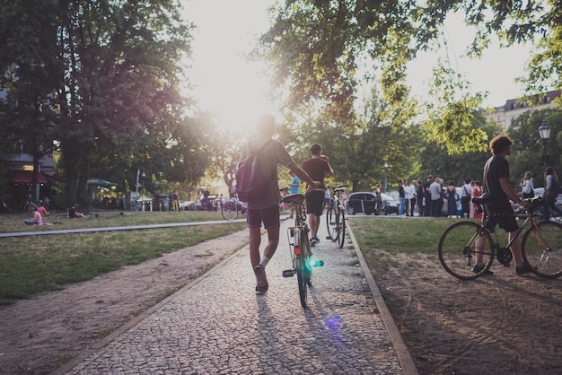 Foto vista traseira de homens com bicicleta em uma calçada no parque