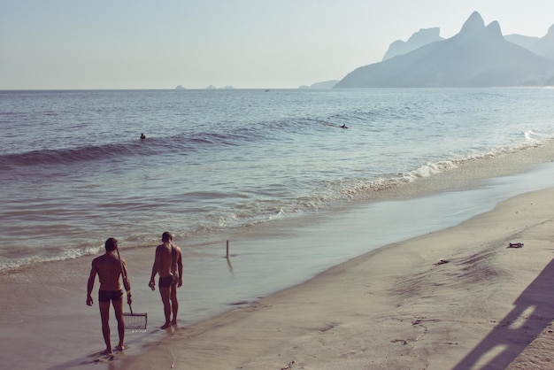 Vista traseira de homens sem camisa de pé na praia