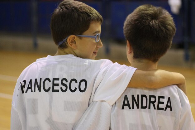 Vista traseira de irmãos com o braço em volta vestindo camiseta com texto