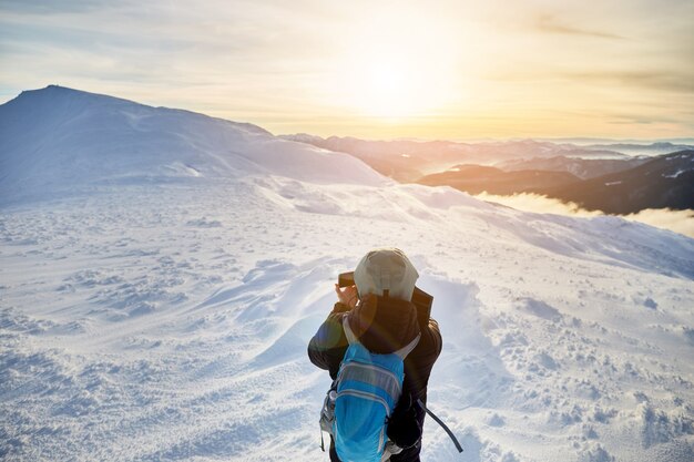 Vista traseira de jovem fazendo foto de montanhas de inverno