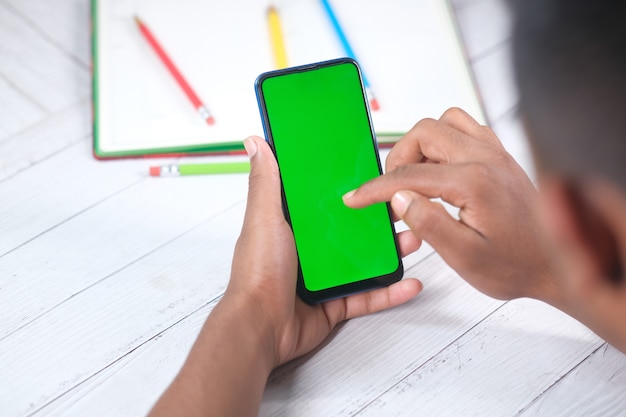 vista traseira de jovem usando telefone inteligente na mesa