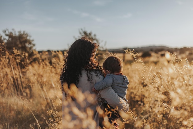 Vista traseira de mãe e filha por plantas contra o céu