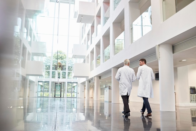 Vista traseira de médicos conversando enquanto caminham pelo hospital