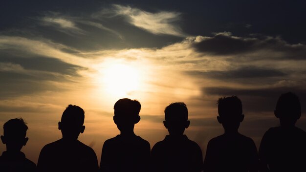 Vista traseira de meninos em silhueta de pé contra o céu durante o pôr do sol