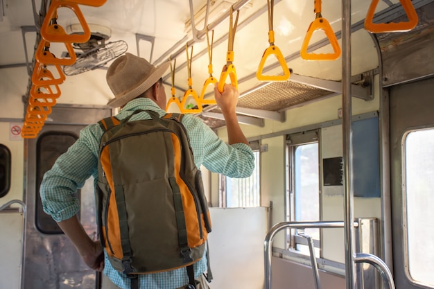 Foto vista traseira, de, mochileiros asiáticos, segurando, corrimão, dentro, a, trem público, ligado, férias