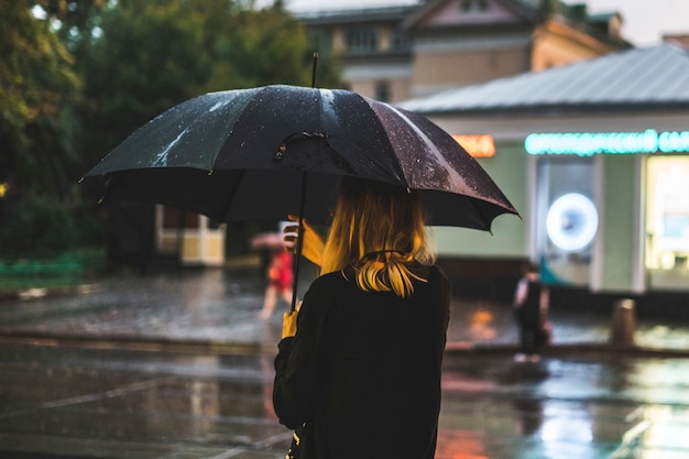 Vista traseira, de, mulher caminhando, durante, a, chuva, cidade