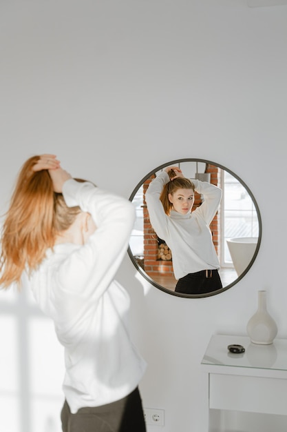 Vista traseira de mulher com os braços levantados de pé contra um fundo branco