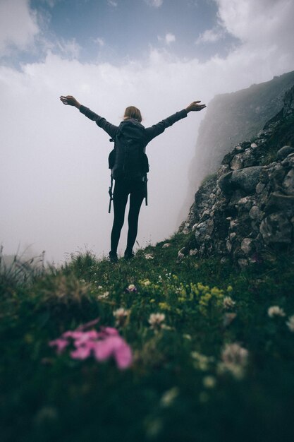 Foto vista traseira de mulher com os braços levantados de pé na paisagem contra o céu