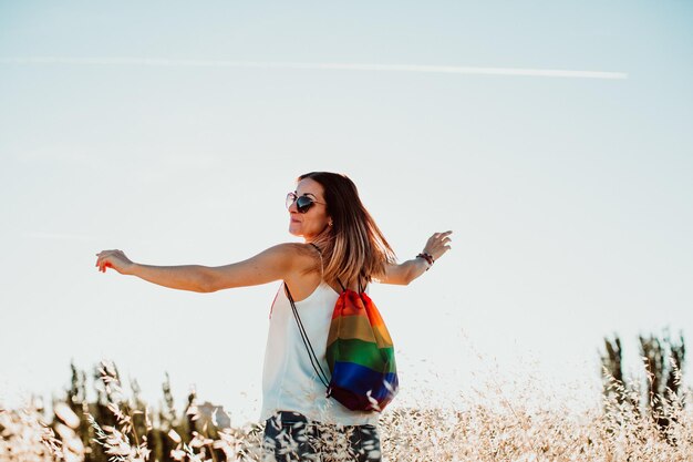 Foto vista traseira de mulher com saco multicolorido de pé na terra contra o céu