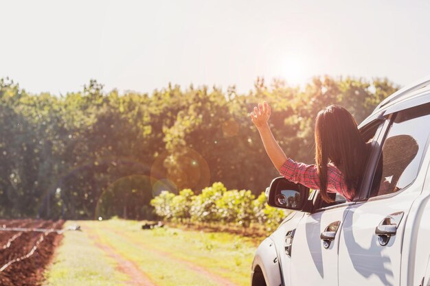 Vista traseira de mulher fazendo gestos através da janela do carro contra as árvores