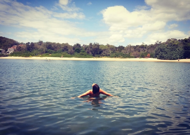 Foto vista traseira de mulher relaxando no lago contra o céu