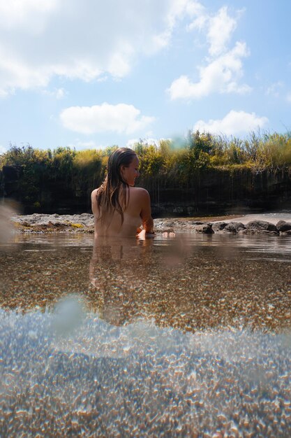 Foto vista traseira de mulher sem camisa nadando no lago contra o céu