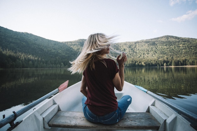 Foto vista traseira de mulher sentada em um barco contra o lago