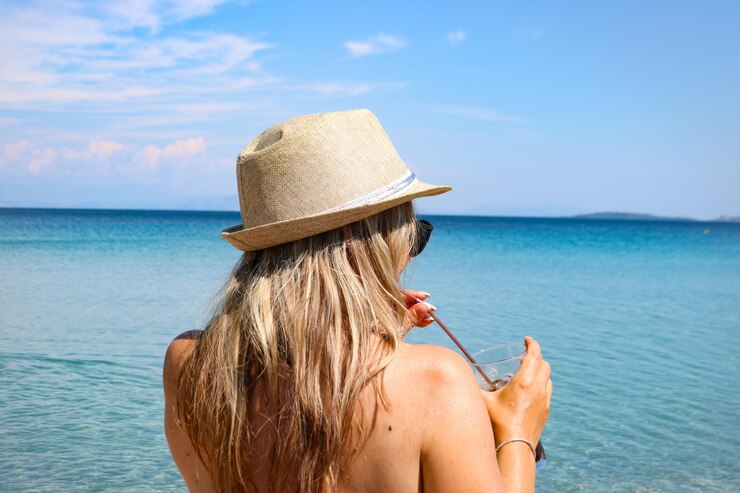 Foto vista traseira de mulher usando chapéu contra o mar