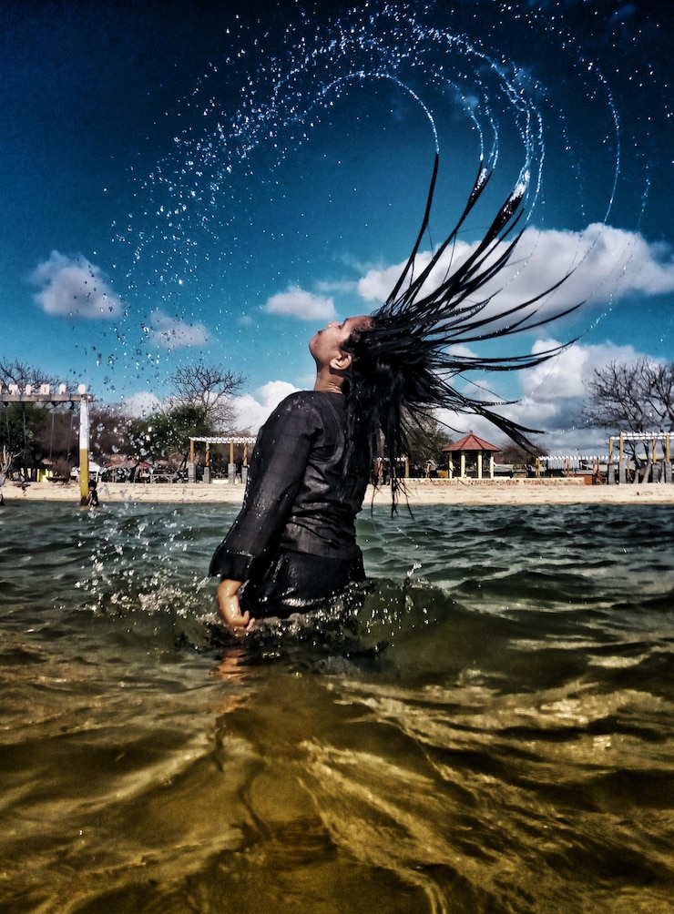 Foto vista traseira de mulher virando o cabelo no mar