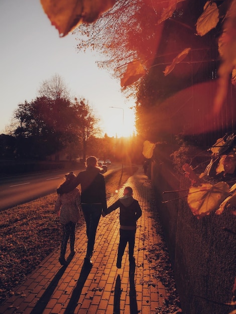 Foto vista traseira de pessoas caminhando na trilha contra o céu durante o pôr do sol