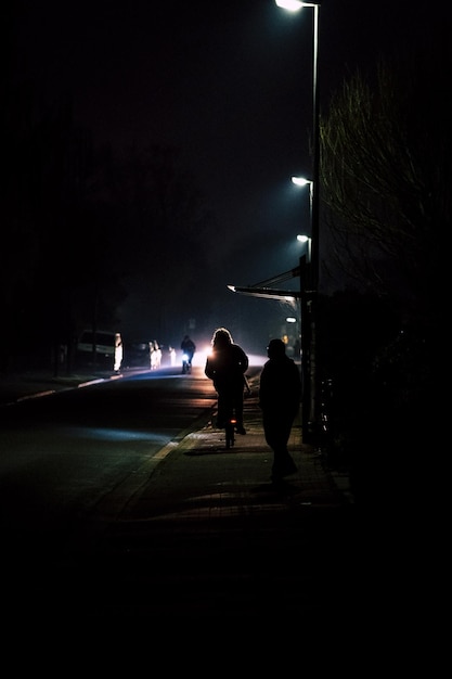 Foto vista traseira de pessoas em silhueta em uma rua iluminada à noite