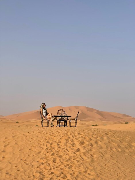 Foto vista traseira de pessoas na areia no deserto contra o céu claro
