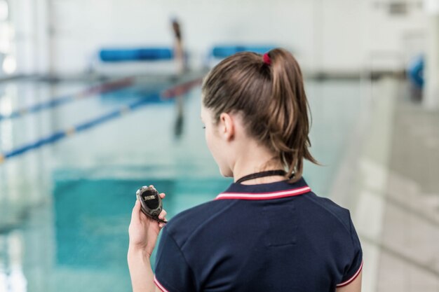 Vista traseira, de, treinador, olhar, cronômetro, em, a, piscina