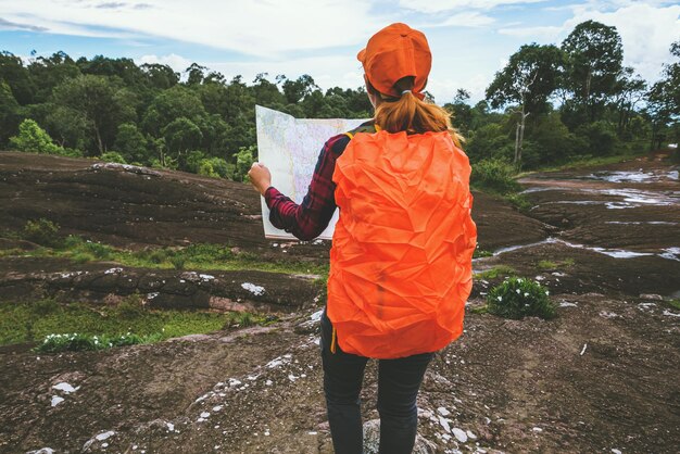 Vista traseira de um caminhante segurando um mapa enquanto está de pé contra o céu