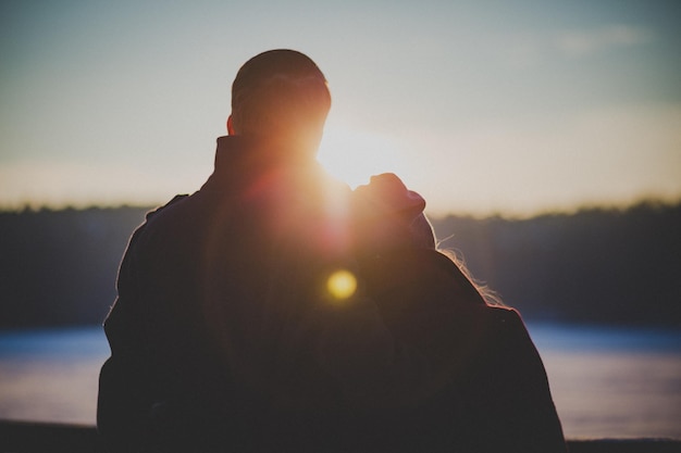 Foto vista traseira de um casal assistindo ao pôr do sol