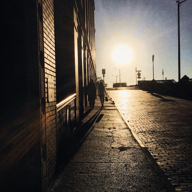 Foto vista traseira de um casal caminhando na rua contra o céu durante o pôr do sol