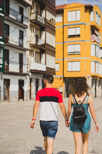 Vista traseira de um casal de mãos dadas caminhando na rua