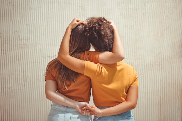 Vista traseira de um casal de mãos dadas enquanto está de pé contra a parede