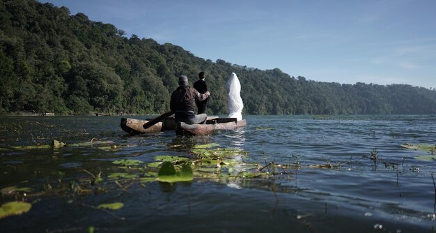 Vista traseira de um casal em um barco no lago contra o céu