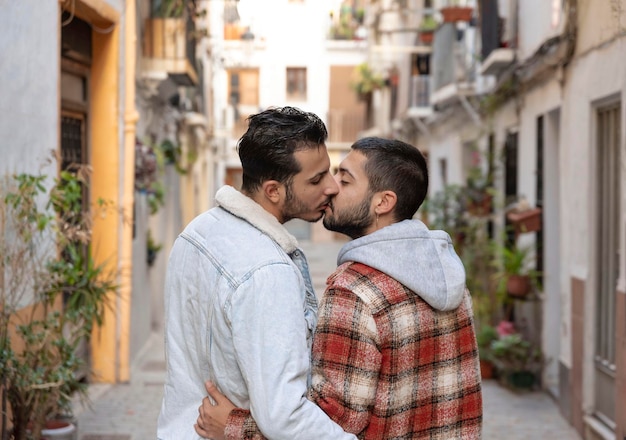 Vista traseira de um casal gay apaixonado andando na rua abraçando e beijando