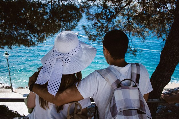 Foto vista traseira de um casal junto a uma árvore na praia