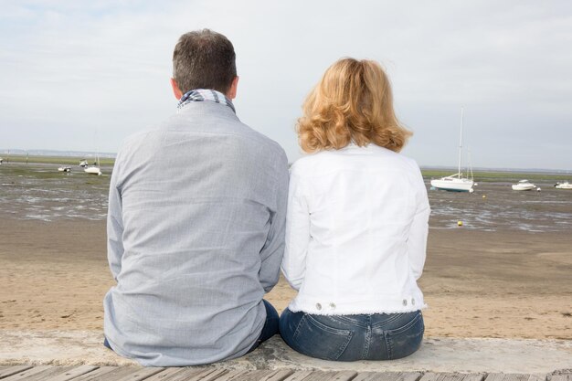 Vista traseira de um casal romântico sentado em um cais