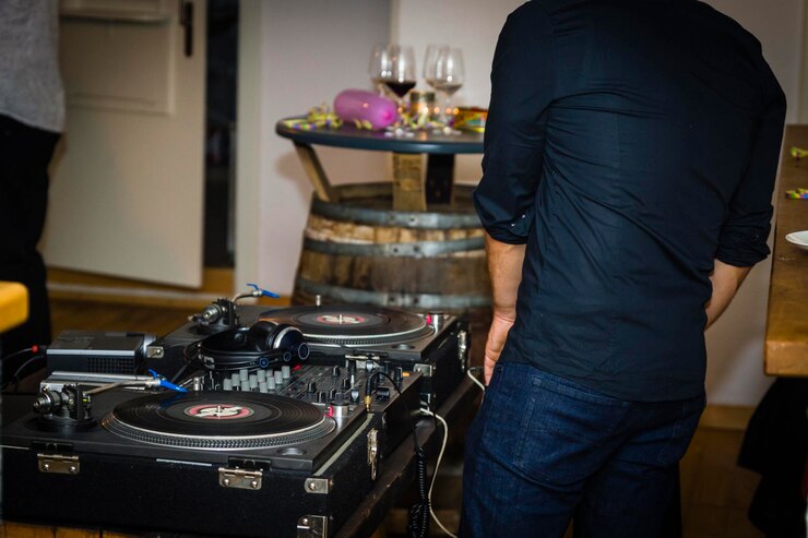 Foto vista traseira de um dj de pé junto ao mixador de som