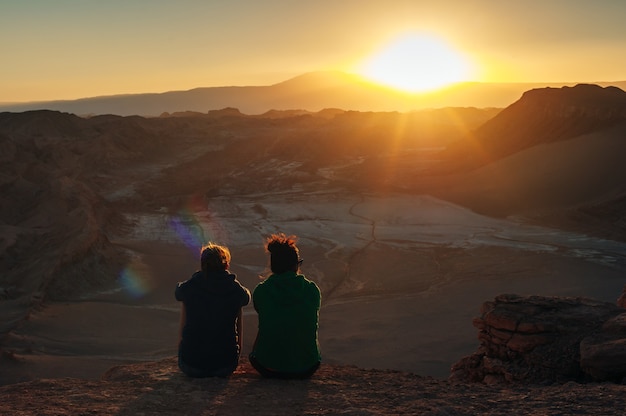 Vista traseira de um grupo de amigos, juntos em uma montanha, olhando para o amanhecer ao nascer do sol